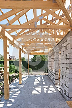 Building house from aerated concrete building blocks. New residential wooden construction home framing against a blue sky.