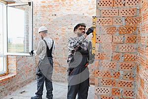 Building house construction workers installing window and checking wall