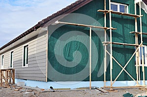 Building house with wall insulation, waterpfoof membrane, plastic siding, guttering and foundation insulation with styrofoam.