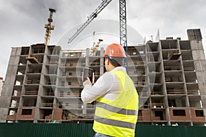 Building inspector holding digital tablet and inspecting building site