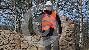 Building inspector talking on cell phone at the ruins of old building