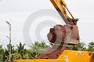 Building Machines: Digger loading trucks with soil. Excavator loading sand into a dump truck.