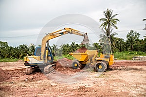 Building Machines: Digger loading trucks with soil. Excavator loading sand into a dump truck.