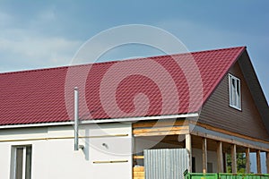Building new red metal roof house construction. Metal roof tiles roofing construction