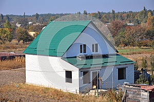 Building new white bricks country house with green metal roof with roof protection from snow board on house construc