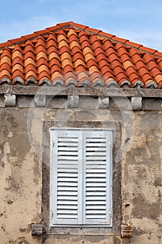 Building with orange roof tiles and wodden shuttered window