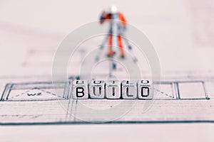 Building plan with the word build on beads and a model worker