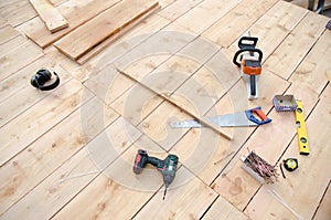 Building a porch, balcony floor with brown wooden planks. the floor and some tools including a drilling machine