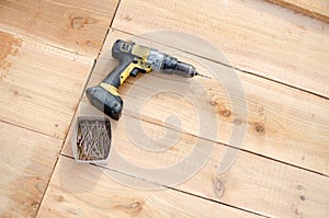 Building a porch, balcony floor with brown wooden planks. the floor and some tools including a drilling machine