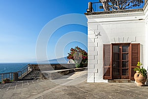 Building on the rocks surrounded by the sea under a blue sky in Sorrento, Italy
