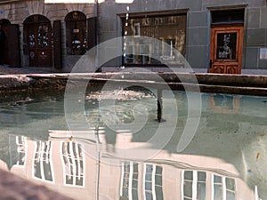 Building`s reflection in the water of a fountain in Fribourg, Switzerland.