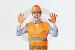 Building sector and industrial workers concept. Cheerful smiling asian builder, construction manager at factory wearing
