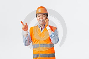 Building sector and industrial workers concept. Smiling asian engineer, construction manager in reflective clothings and