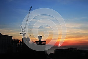 Building silhouettes and Industrial construction cranes on beautiful sunset