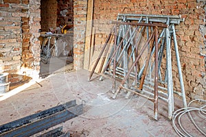 a building site, 2 scaffolding trestles lean against a brick wall
