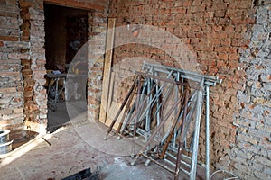 a building site, 2 scaffolding trestles lean against a brick wall