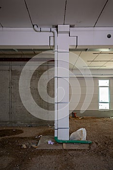 On  building site a drain pipe is led along a pillar