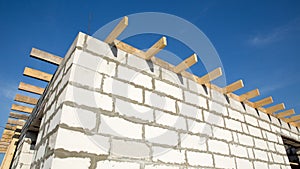 Building site of a house under construction. corner unfinished house walls made from white aerated autoclaved concrete blocks