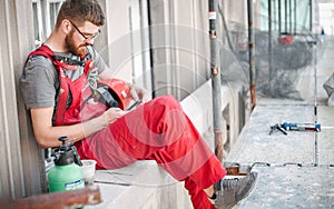 Building site worker on the scaffolding using mobile phone