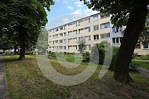 The building is slightly behind lawn and trees