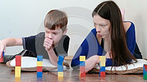 Building a small and big towers from blocks and cubes. Mom and son playing together with wooden colored education toy