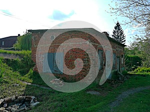 Building, small, old and abandoned, its windows are closed with steel sheets