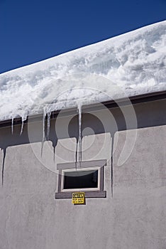 Building With Snow And Icicles And Caution Sign