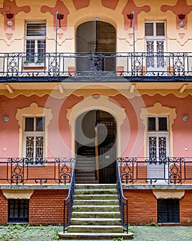 a building with stairs up to some bushes and flowers in front