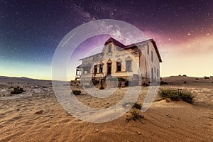 A building standing under the stars at night in a ghost town in the desert of Namibia.