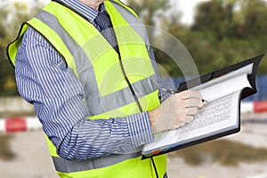 Building surveyor in hi vis checking data in site folder photo