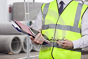 Building surveyor in high visibility vest carrying work folders