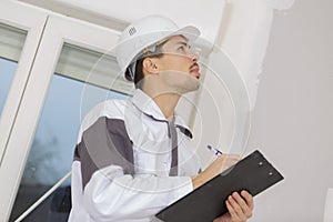 Building surveyor writing on clipboard on construction site