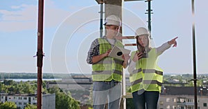 Building technology and people concept - smiling builders in hardhats with tablet pc computer outdoors.