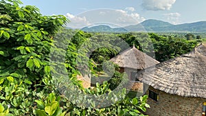 a building with a thatched roof surrounded by trees and hills