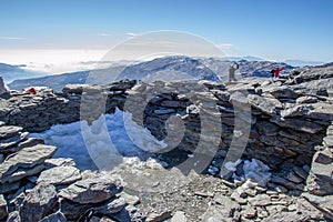 Building on the top of Mulhacen with snow with people in the background photo