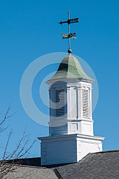 Building topping white cupola with green tin roof against a deep blue sky.
