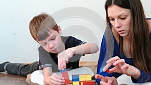 Building a towers from blocks and cubes. Mom and son playing together with wooden colored education toy blocks lying on