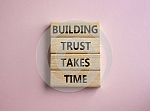 Building Trust takes Time symbol. Wooden blocks with words Building Trust takes Time. Beautiful pink background. Business and