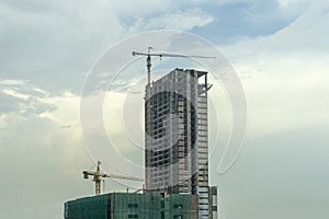 Building under construction, Condo construction, Building site with yellow cranes, and blue sky background
