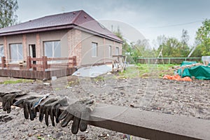 The building under construction and dirty working gloves on the foreground