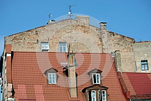 Building wall in bad condition above red metal roof in old town of Riga
