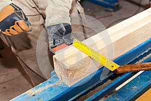 Building a wall for frame house. Worker make marks for cutting timber.