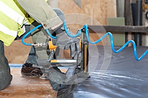 Building a wall for frame house. Worker use autofeed staple gun for attaching a vapor barrier.