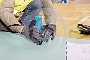 Building a wall for frame house. Worker use Laminate Trimmer for cutting drywall.