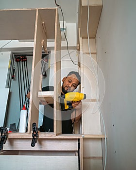 Building a wardrobe. Man using Framing Nailer to attach wooden plywoods