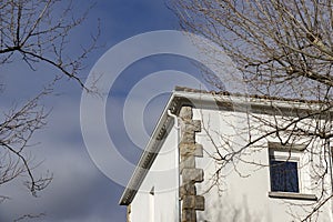 Building. White colored building next to some bare and leafless trees in the surroundings.