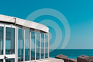 A building with windowed walls and a white roof on the harbour with the Mediterranean sea view Italy, Europe