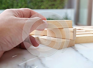 Building wooden block puzzle on the marble table / Copy space and Closeup hand try to build the blocks wood game