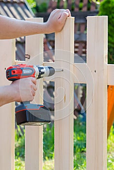 Building a wooden fence with a drill and screw. Close up of his