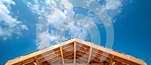 Building a wooden structure under construction under a blue sky with scattered lumber and clouds.